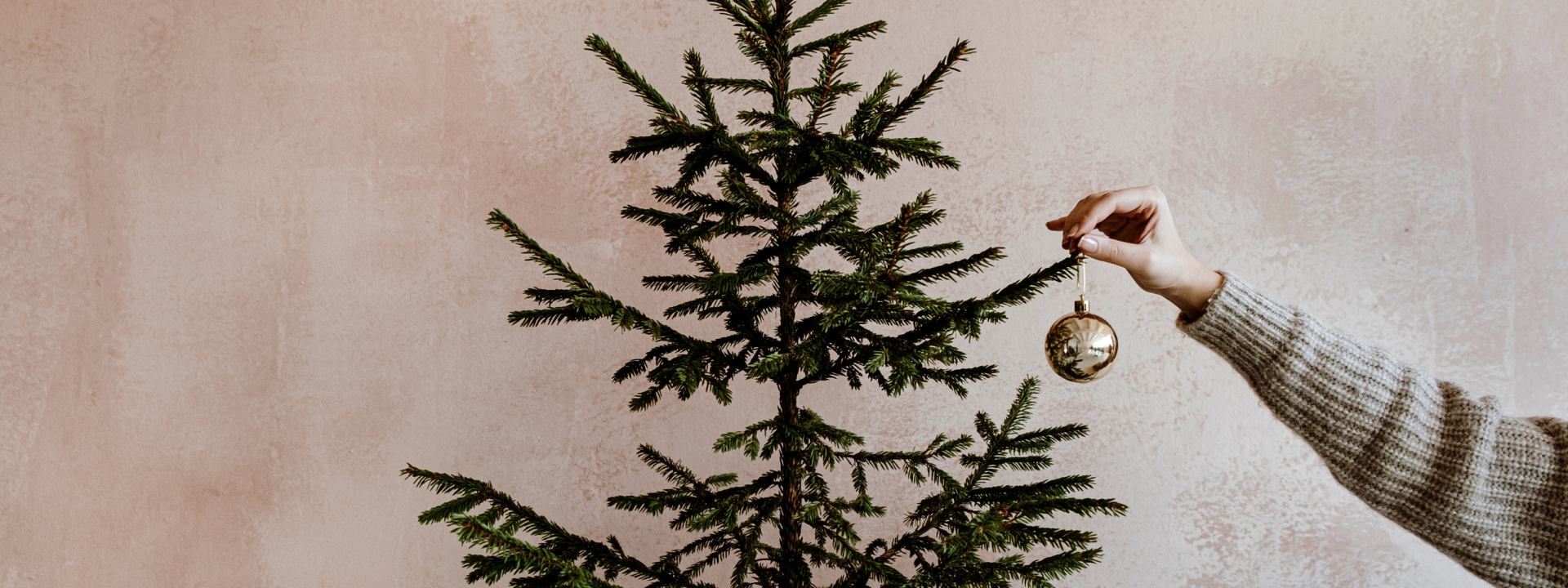 Käsi asettamassa koristepalloa joulukuuseen Käsi asettamassa koristepalloa joulukuuseen