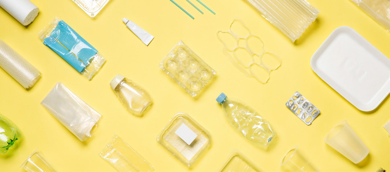 Tyhjiä muovipakkauksia keltaisella taustalla