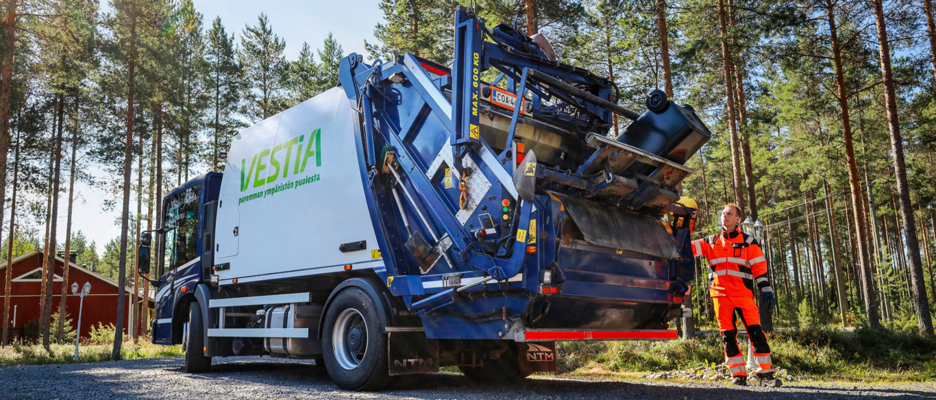 Jäteauton kuljettaja tyhjentää omakotitalon jäteastiaa jäteautoon.