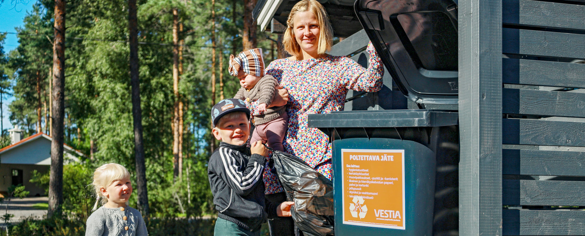 Kuluttaja-asiakkaat Äiti ja lapset viemässä roskapussia jäteastiaan.