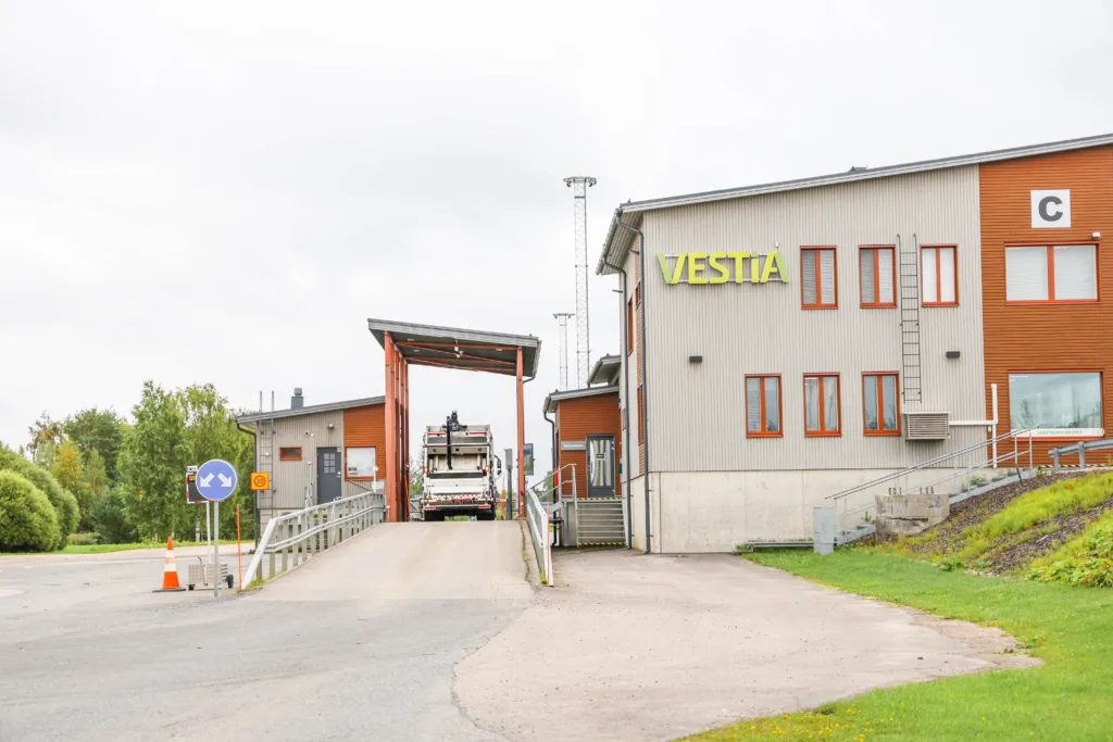 Jäteauto vaa'alla, takaapäin kuvattuna. Oikealla näkyy Vestian palvelurakennus ja sen yläreunassa Vestian logo.