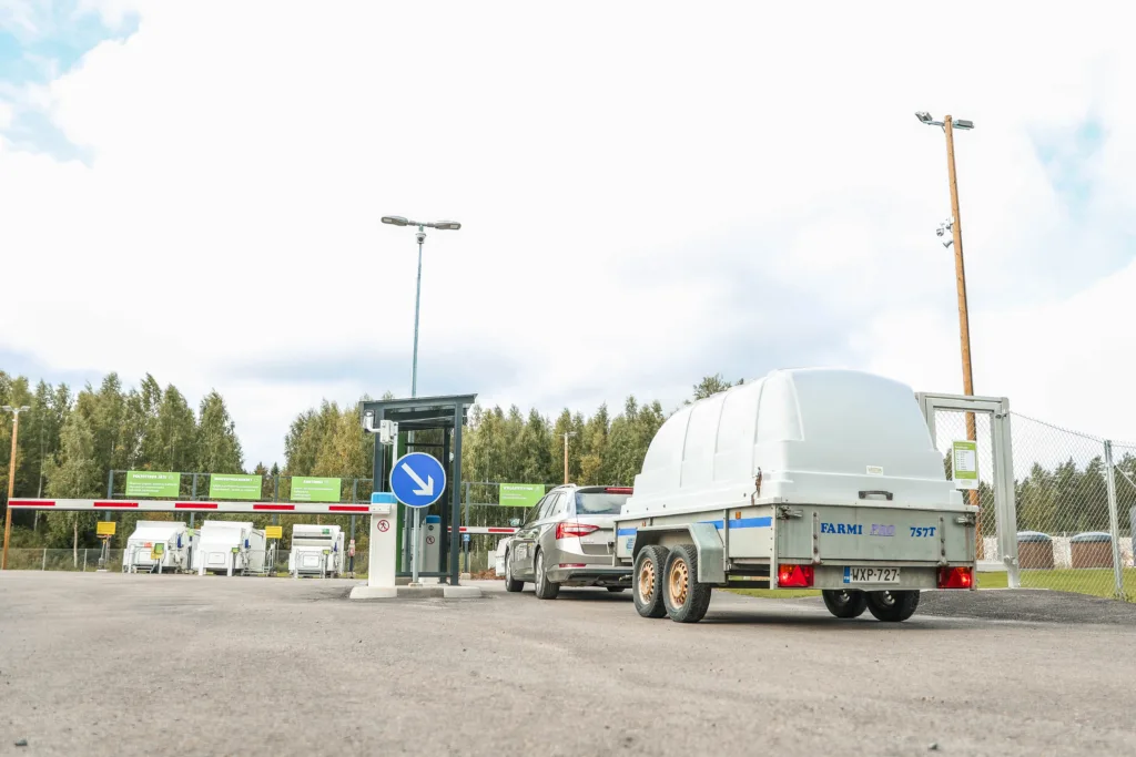 Auto pysähtyneenä lajittelupihan portille peräkärry perässä