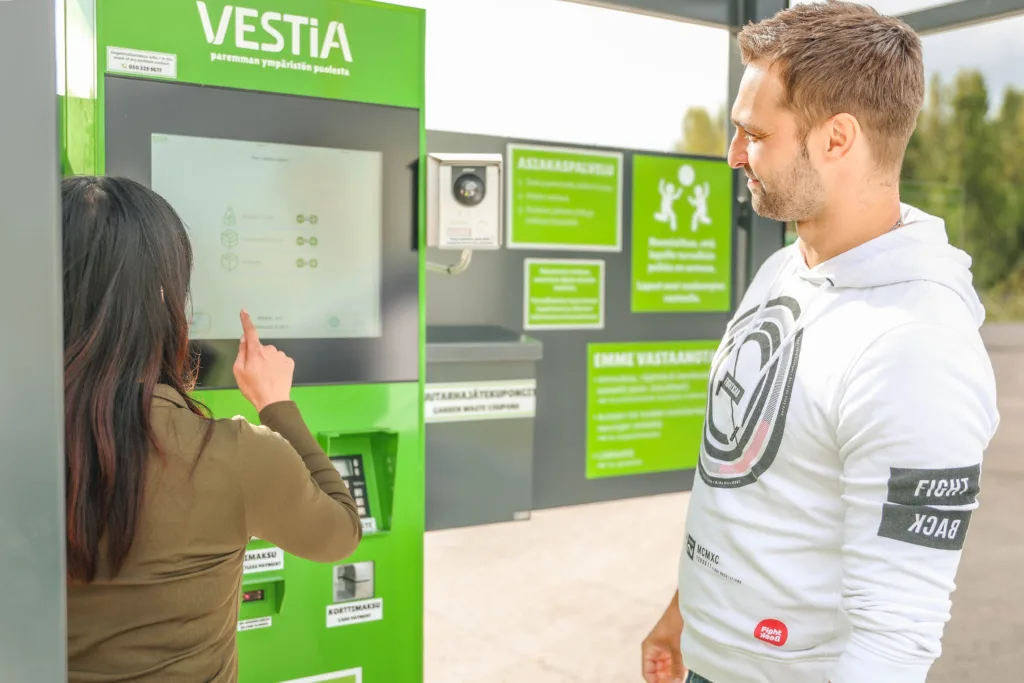 Kaksi henkilöä Vestian lajittelupihan itsepalveluautomaatilla ilmoittamassa jätteitä