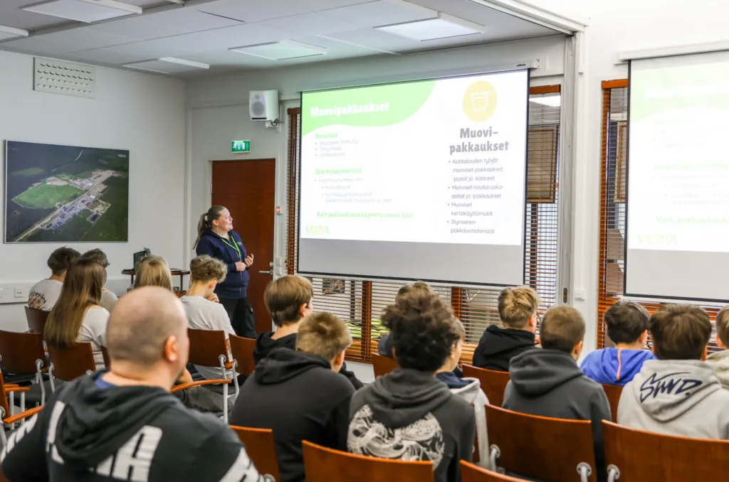 Kierrätysneuvoja auditoriossa pitämässä kierrätysneuvontaa joukolle lapsia