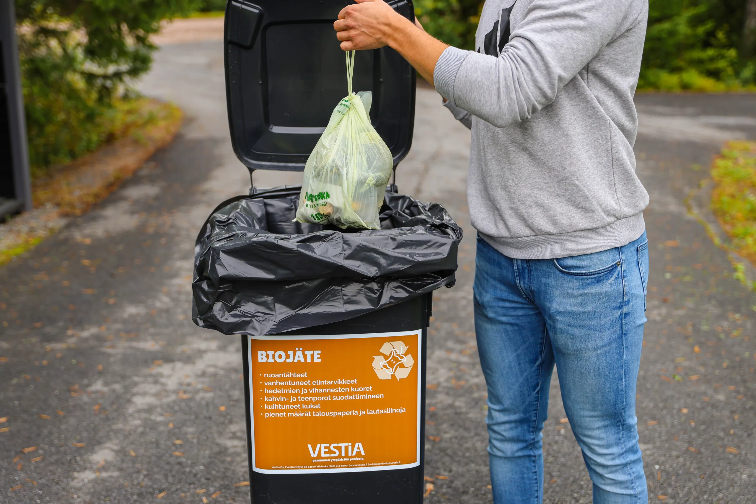 Henkilö laittamassa biojätepussia biojäteastiaan.